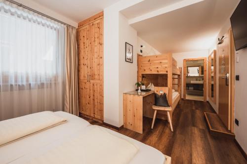 a bedroom with a bed and a desk with a chair at Hotel Bischofhof in Chiusa