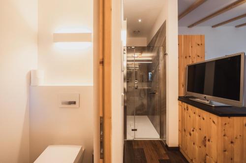 a bathroom with a toilet and a television and a shower at Hotel Bischofhof in Chiusa