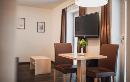 a room with a table with chairs and a tv at Hotel Bischofhof in Chiusa