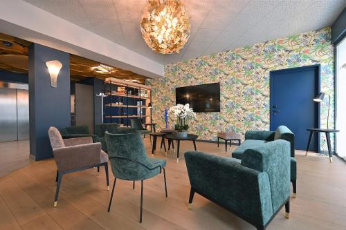 une salle d'attente avec des chaises, des tables et une télévision dans l'établissement Dali Hôtel Perpignan - Restaurant, à Perpignan