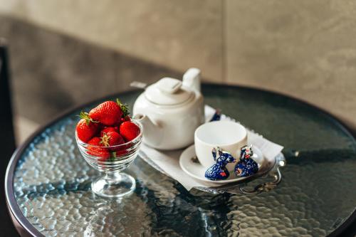 a glass table with a cup and a bowl of strawberries at TipTop Hotel CITY CENTER in Chişinău