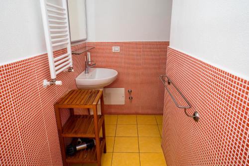 a bathroom with a sink and orange tiled walls at Casa Junno in Mattinata