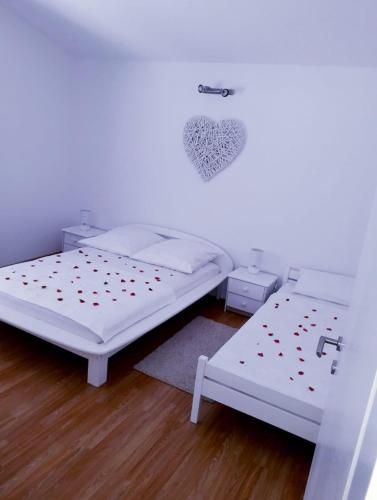 two beds in a room with white walls and wooden floors at Apartment Relax in Vir
