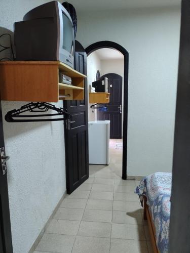 un pasillo con una puerta y una TV en un estante en Suites Mar Azul Prainha, en Arraial do Cabo