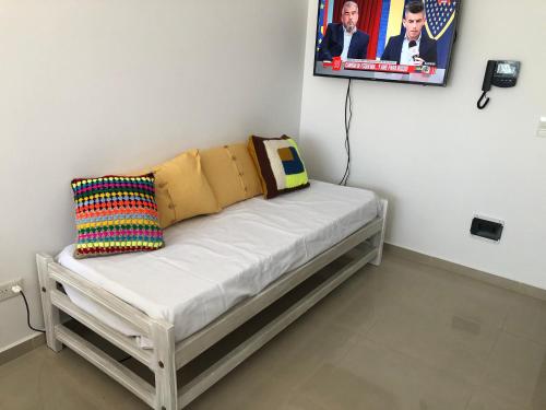 a white bench with a pillow and a picture on the wall at Departamento Centrico VDL in Puerto Madryn