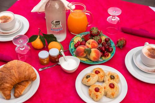 a red table with plates of breakfast food and orange juice at B&B La Mortella in Albanella