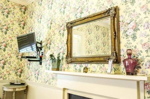 a mirror on a wall with floral wallpaper at Early Inn at the Grove in Rocky Mount
