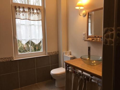 een badkamer met een wastafel, een toilet en een raam bij VILLA HENRI in Flavy-le-Martel