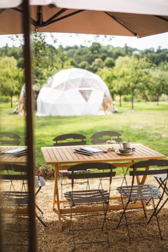 a wooden table and chairs with a tent in the background at Locations - Domaine Le Coq Enchanté in Cambremer