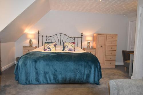 a bedroom with a large bed with a blue blanket at Brampton Luxury Annexe Apartment in Huntingdon