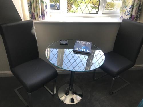 two chairs and a glass table with a book on it at Brampton Luxury Annexe Apartment in Huntingdon