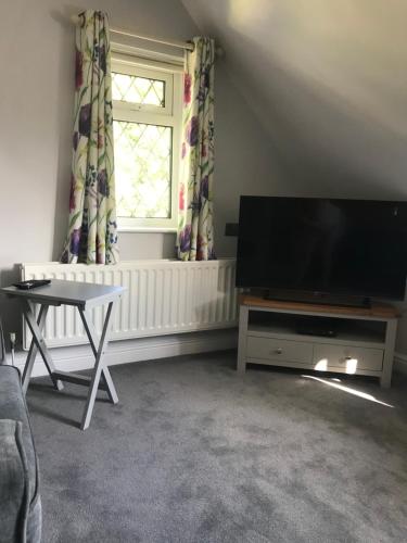 a living room with a flat screen tv and a table at Brampton Luxury Annexe Apartment in Huntingdon