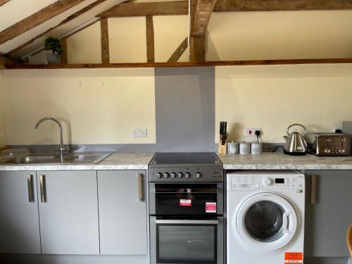 a kitchen with a sink and a washing machine at The Cow Shed 1BR-Sleeps4-Parking-PetsOK in Bradwell on Sea