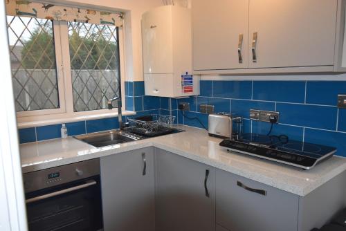 a kitchen with white cabinets and blue tiles at Brampton Luxury Annexe Apartment in Huntingdon