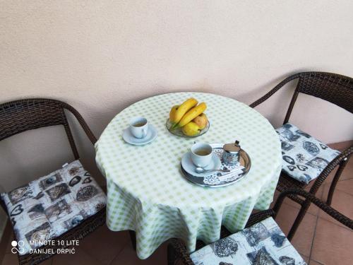 a table with a bowl of bananas and cups on it at Apartments Drpic in Gabonjin