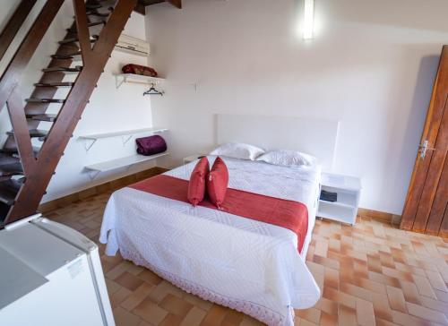 um quarto com uma cama com almofadas vermelhas em Pousada Cachoeira Poço Encantado em Alto Paraíso de Goiás