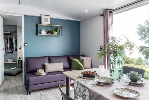 a living room with a purple couch and a table at Chênefleur in Tintigny