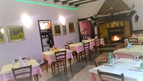 un ristorante con tavoli, sedie e un camino di HOTEL RISTORANTE VITTORIA dal 1920 a Marzio