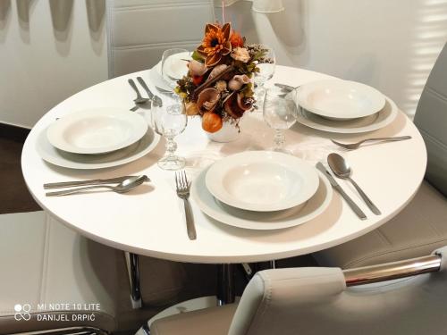 a white table with plates and silverware on it at Apartments Drpic in Gabonjin