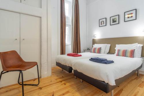 a hotel room with two beds and a chair at LV Premier Apartments Baixa- FI in Lisbon