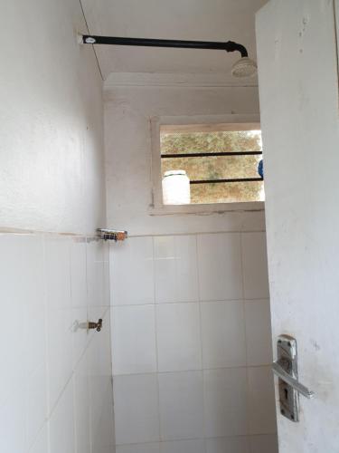 baño con ventana y ducha de azulejos blancos en Captivating 3-Bed House in Moshi Town, en Uru