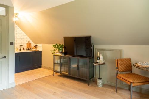 a living room with a television and a table and chairs at Beautiful Luxury Property in the Surrey Hills in Cranleigh