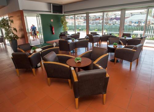 a waiting room with chairs and tables and windows at Oasis Belorizonte in Santa Maria