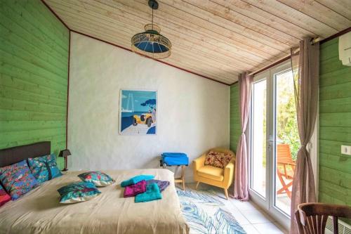 um quarto com paredes verdes, uma cama e uma janela em Merlettes des Sables em Yves