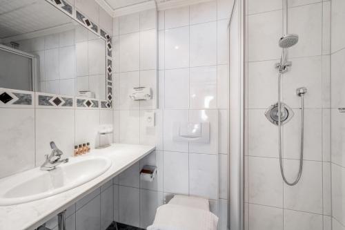 a white bathroom with a shower and a sink at Hotel Sölderhof in Sölden