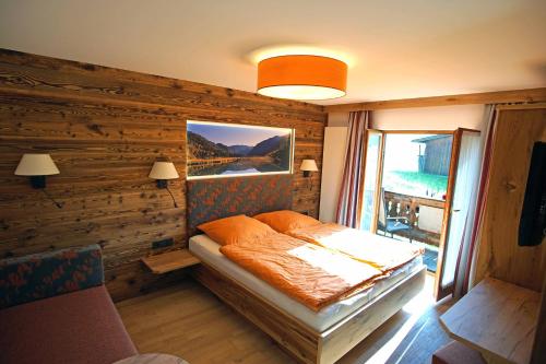 1 dormitorio con 1 cama en una pared de madera en Haus Zauner, en Reit im Winkl