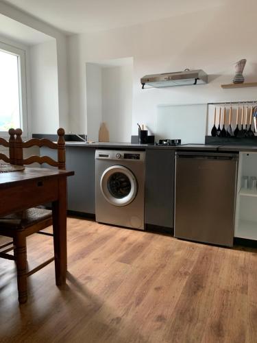 a kitchen with a washing machine and a table at chez LULU appartement neuf au coeur de cozzano in Cozzano