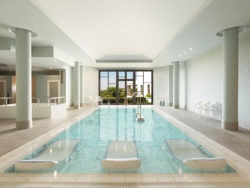 a large swimming pool with two chairs in a building at Hotel Fuerte El Rompido in El Rompido