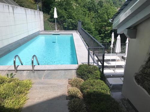 a large swimming pool with a staircase and a house at Casa di campagna Tony con piscina e vista lago in Gravedona