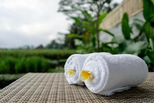 two towels with flowers on top of a table at Poka Villa & Spa in Ubud