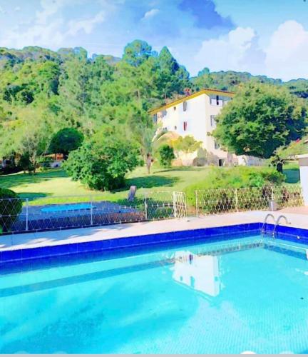 a large swimming pool with a house in the background at Pousada Jupter in Teresópolis