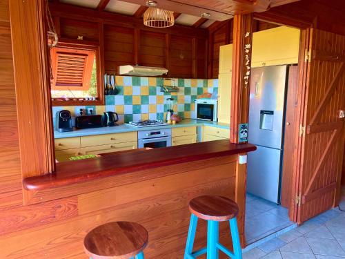 a kitchen with a counter and a refrigerator and stools at Villa Nature caraïbe lodge, vue mer, piscine privée in Deshaies