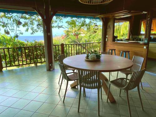 a table and chairs on a porch with a view of the ocean at Villa Nature caraïbe lodge, vue mer, piscine privée in Deshaies