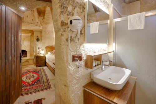 格雷梅的住宿－鬱金香洞穴套房酒店，一间带水槽的浴室和一张位于客房内的床