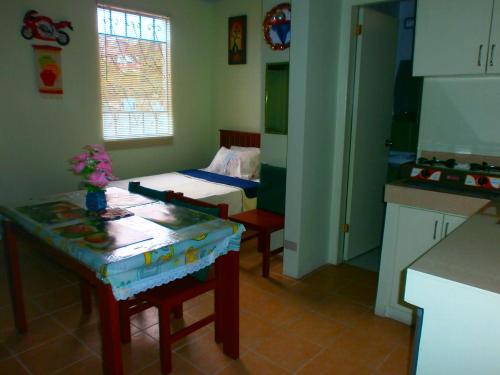 a kitchen with a table and a bed in a room at Lyn's Do Drop Inn Transient House in Baguio