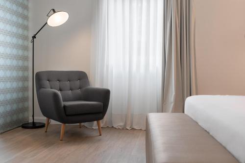 a bedroom with a chair in front of a window at Eurostars Marqués de Vallejo in Logroño