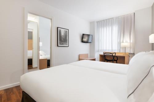 a white hotel room with a bed and a mirror at Eurostars Marqués de Vallejo in Logroño