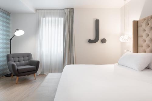 a bedroom with a king sized bed and a chair at Eurostars Marqués de Vallejo in Logroño