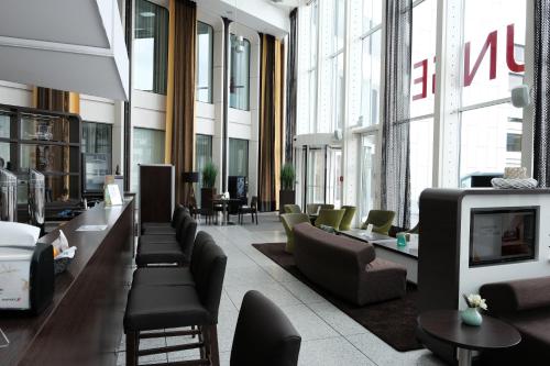 a lobby with couches and chairs in a building at Webers - Das Hotel im Ruhrturm in Essen