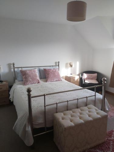 a bedroom with a bed with pink pillows and a chair at Benview Bed and Breakfast in Staffin