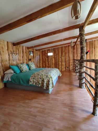 1 dormitorio con 1 cama en una habitación con paredes de madera en Proyecto COYAM, cabañas lofts, tinas privadas, sendero por el bosque en Villarrica