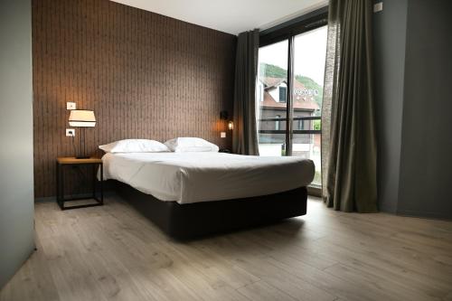 a bedroom with a bed and a large window at Hôtel Les Muses in Annecy