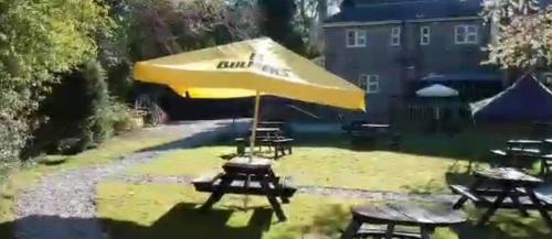 a yellow umbrella and picnic tables in a yard at The Heights Bunkhouse in Llanberis