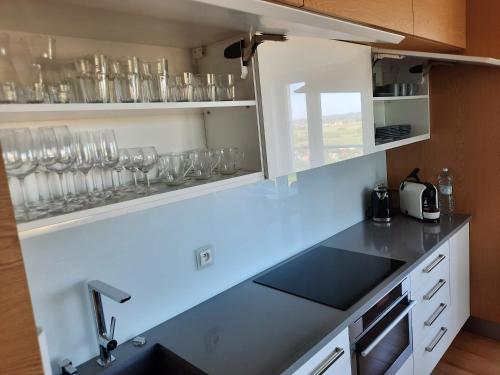 a kitchen with a counter with glasses on the shelves at Aqua Apartments Sunset in Reda