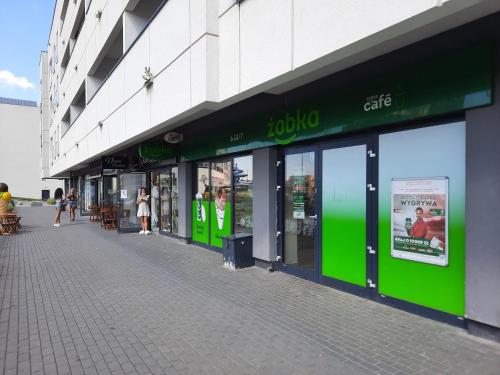 a store with green signs on the side of a building at Aqua Apartments Sunset in Reda