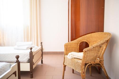 a bedroom with a wicker chair and a bed at L'angolo di Gioia in Montecarlo